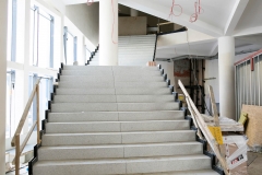 Białe schody o czarnym wykończeniu po bokach prowadzące na poziom pierwszy.