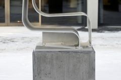 Rzeźba autorstwa Donata Szulińskiego.  Wykonana z cienkich warstw aluminium przywodzi na myśl niedokończoną literę "S". Widziana z profilu. Pusta w środku. Umieszczona na kamiennym graniastosłupie.