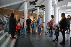 Grupa osób z małymi dziećmi w holu. Po lewej na pierwszym stopniu schodów stoi Renata Rudowicz z CKiS.