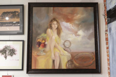 Obraz przedstawiający siedzącą na stole dziewczynę. Obok niej ogromny kielich z owocami. W rogu obrazu tarcze zegarów.