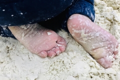 Zbliżenie na dziecięce stopy w piasku.