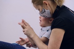 Matka uczy dziecko klaskać, trzymając w swoich jego dłonie.