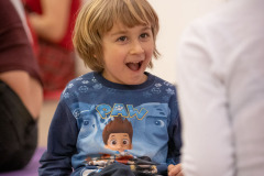 Dziecko w koszulce z postacią i napisem PAW szeroko otwiera usta.