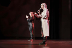 Na scenie Marta Duszyńska z CKiS w Koninie z podkładką i mikrofonem. W głębi kadru tłumaczka języka migowego.