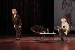 Na scenie Maria Peszek w ukłonie. Roześmiana Marta Duszyńska siedzi w fotelu. Obok niej drugi fotel, stolik, a na nim dwie szklanki i karafka.