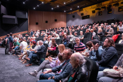 Zdjęcie grupowe. Publiczność siedząca w fotelach sali widowiskowej.