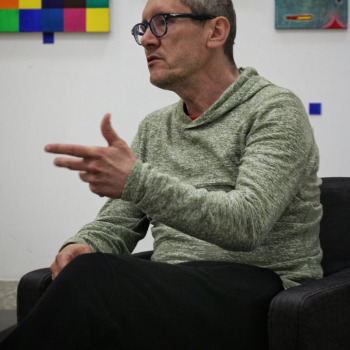Zdjęcie portretowe. Robert Brzęcki mówi i gestykuluje lewą dłonią.