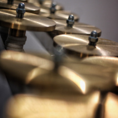 Zbliżenie na dwa rzędy metalowych talerzy, instrumentów perkusyjnych. 
