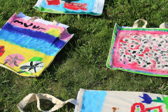 Na trawie rozłożone torby z materiału pomalowane przez uczestników zajęć.
