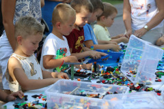 Dzieci, a przed nimi klocki Lego wysypane z plastikowych pudełek.