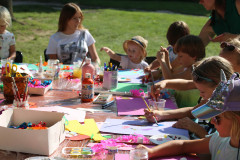 Dzieci malują przy stoliku. Na blacie materiały plastyczne.