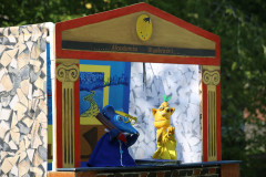 Dekoracja sceniczna na kształ antycznego teatru z napisem Akademia Wyobraźni. Występują pacynki: niebieska mysz i żółty stwór.