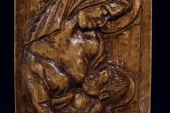 Lakierowana jasnobrązowa płaskorzeźba przedstawiająca Matkę Boską, która karmi Dzieciątko.