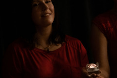 Uśmiechnięta kobieta w czerwieni trzyma lampion.