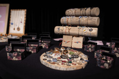 Na stoliku, w pudełkach i na kawałakach drewna wyłożona biżuteria.