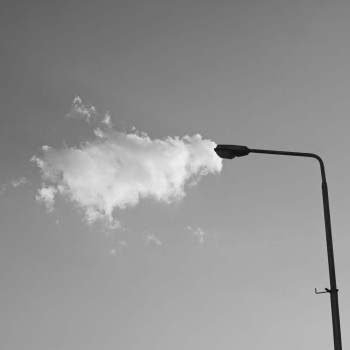 Chmura stykająca się z latarnią. Zdjęcie czarno-białe.