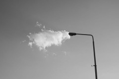Chmura stykająca się z latarnią. Zdjęcie czarno-białe.