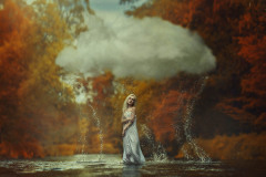Kobieta w wodzie. Nad nią chmura. W tle jesienne drzewa.