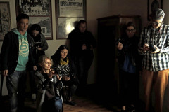 Grupa osób z aparatami. Za nimi na ścianie zdjęcia w ramach. Na jednym napis Zofia Urbanowska.