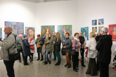 Goście wernisażu podczas rozmów. Na białych ścianach wyeksponowane prace Krystyny Ruminkiewicz. Niemal wszystkie to kobiece portrety.