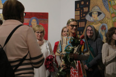 Wśród gości wernisażu stoi Krystyna Ruminkieiwcz z kwiatami.