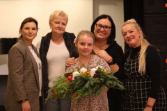 Do zdjęcia pozują uczestniczki warsztatów i Renata Rudowicz. Dziewczynka stojąca przed nimi prezentuje wieniec.