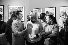 Trzy kobiety rozmawiają ze sobą. Stoją na wprost obiektywu pośród tłumu uczestników wystawy.