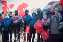 Członkowie grupy rowerowej PTTK CIKLO KT pozują do zdjęcia z Piotrem Korytkowskim. Nad ich głowami unoszą się trzymane na sznurkach czerwone balony w kształcie serca.