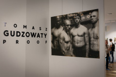 Po prawej zdjęcie czterech umięśnionych mężczyzn. Po lewej napis Tomasz Gudzowaty Proof