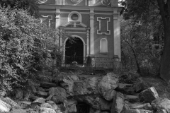 Kaplica grobowa Czartoryskich w Gołuchowie. Widok frontalny. Do otoczonego drzewami budynku prowadzą kamienne schodu. Zdjęcie czarno-białe.