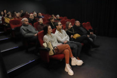 Zdjęcie publiczności w czerwonych fotelach kinowych.