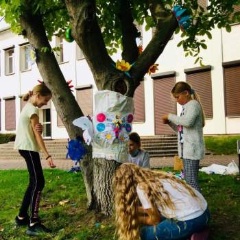 Cztery dziewczynki ozdabiają drzewo przed budynkiem CKiS przy Okólnej.