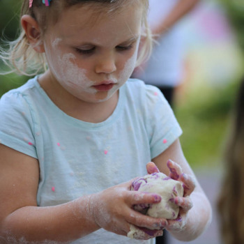 Dziewczynka z białymi śladami na twarzy trzyma w dłoniach kulę z masy solnej.