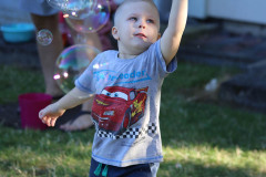 Chłopiec w koszulce z Zygzakiem McQueenem próbuje chwycić bańki mydlane.