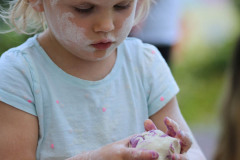 Dziewczynka z białymi śladami na twarzy trzyma w dłoniach kulę z masy solnej.