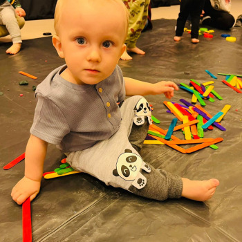 Dziecko bawiące się kolorowymi patykami patrzy w obiektyw.