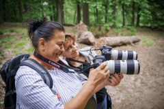 Dwie kobiety trzymają równolegle aparaty stykając je obiektywami.