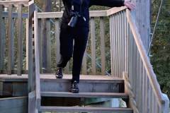 Po drewnianych schodach wieży widokowej schodzi ubrana na czarno Olga Marcinkowska. Na szyi ma przewieszony aparat. Rozkłada szeroko ramiona.